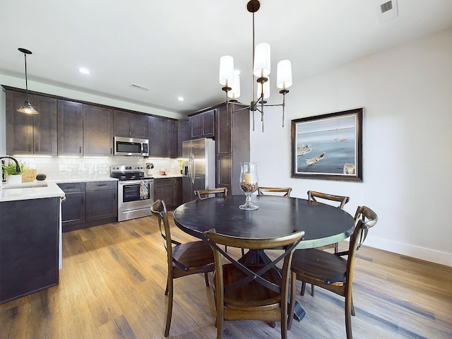 dining area featuring sink, an inviting chandelier, and light wood-type flooring