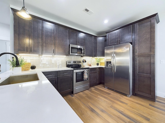 kitchen featuring sink, dark wood-type flooring, stainless steel appliances, backsplash, and pendant lighting