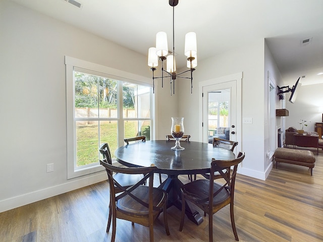 dining area with a wealth of natural light, a chandelier, and hardwood / wood-style flooring