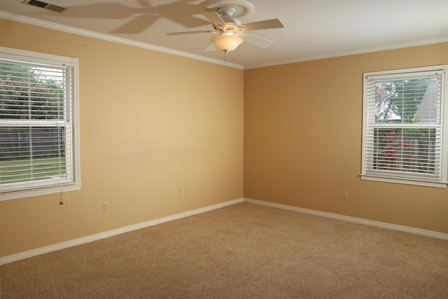 spare room with light colored carpet, visible vents, a ceiling fan, baseboards, and crown molding