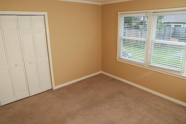 unfurnished bedroom with ornamental molding, light colored carpet, and a closet