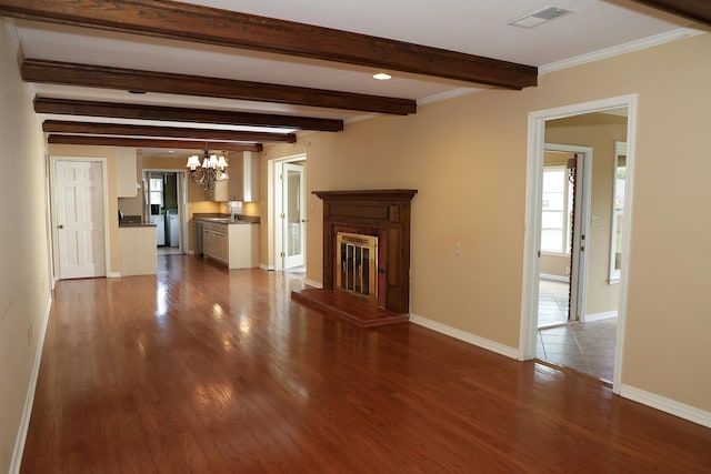 unfurnished living room with beamed ceiling, wood-type flooring, an inviting chandelier, and washer / clothes dryer