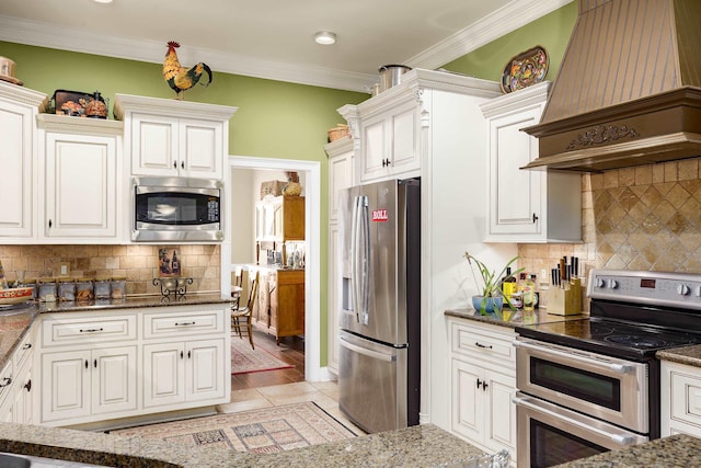  - kitchen with appliances with stainless steel finishes, custom exhaust hood, backsplash, dark stone countertops, and ornamental molding