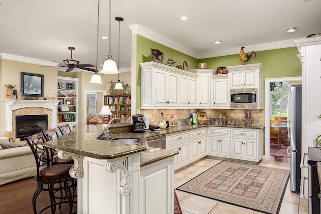  - kitchen featuring appliances with stainless steel finishes, open floor plan, a ceiling fan, decorative backsplash, and a peninsula