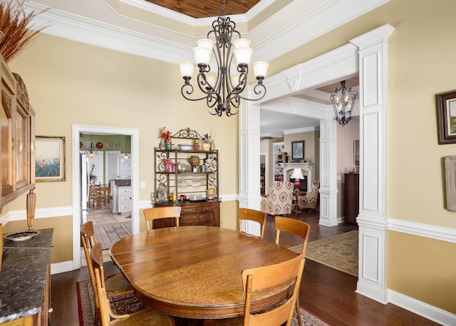  - dining room featuring a chandelier, decorative columns, dark wood finished floors, crown molding, and a raised ceiling