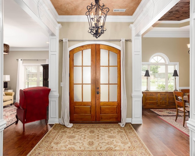  - entrance foyer featuring a chandelier, french doors, wood-type flooring, healthy amount of natural light, and ornamental molding