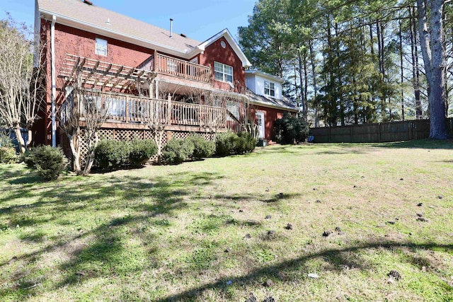 back of house featuring fence, a deck, a lawn, and brick siding