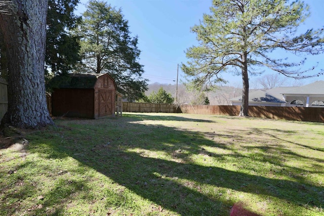 view of yard featuring a shed, fence, and an outbuilding