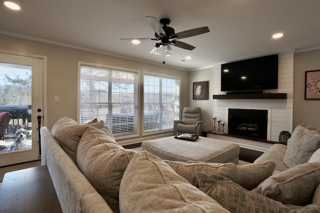 living room featuring plenty of natural light, a fireplace, crown molding, and recessed lighting