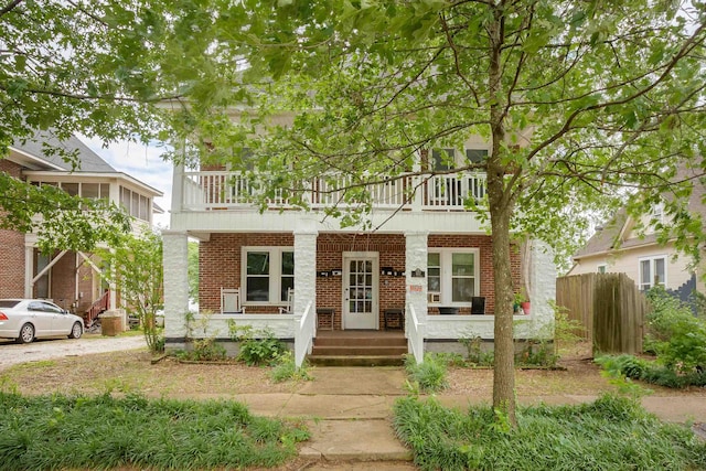 - view of front of house with a balcony, covered porch, and brick siding