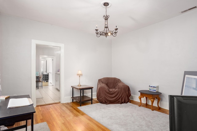  - living area with light wood finished floors and a chandelier
