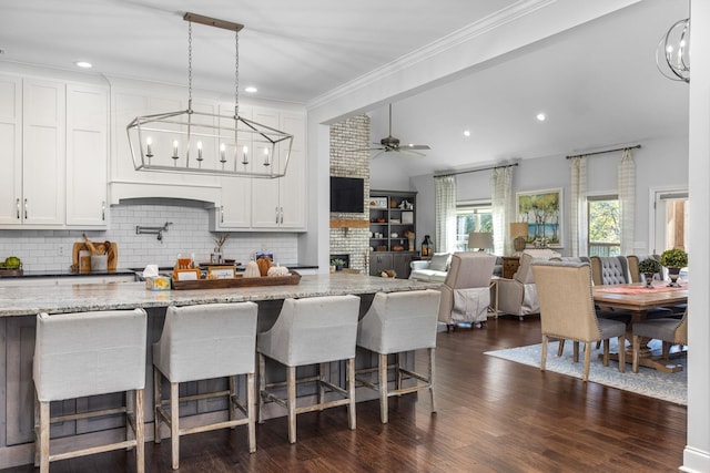 kitchen with pendant lighting, ceiling fan, decorative backsplash, light stone countertops, and white cabinetry