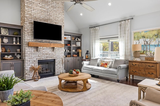 living room featuring ceiling fan, high vaulted ceiling, wood-type flooring, and a brick fireplace