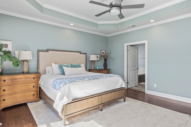 bedroom with connected bathroom, ceiling fan, a raised ceiling, hardwood / wood-style floors, and ornamental molding