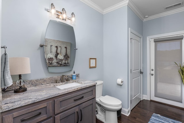 bathroom featuring toilet, vanity, hardwood / wood-style floors, and ornamental molding