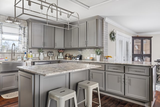 kitchen with gray cabinetry, dark wood-type flooring, sink, light stone countertops, and tasteful backsplash