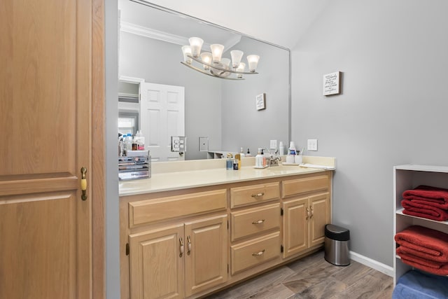 bathroom featuring vanity, wood-type flooring, crown molding, and an inviting chandelier