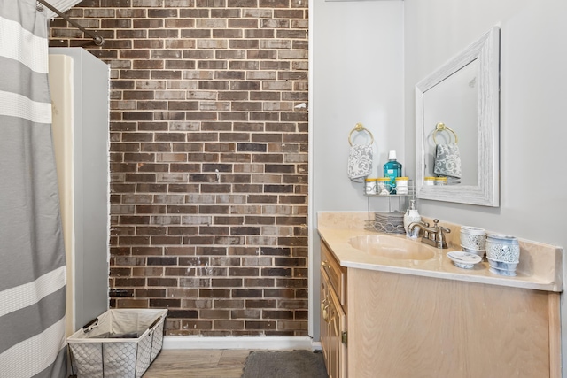 bathroom featuring vanity, brick wall, and hardwood / wood-style flooring