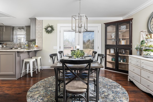 dining space with dark hardwood / wood-style floors, sink, crown molding, and a chandelier