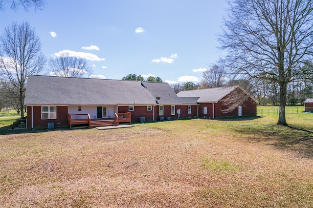 rear view of property with a lawn, a wooden deck, and central AC