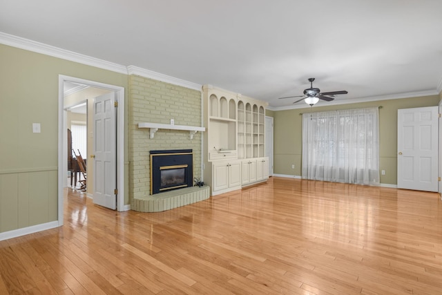 unfurnished living room with crown molding, hardwood / wood-style flooring, ceiling fan, a wealth of natural light, and a brick fireplace