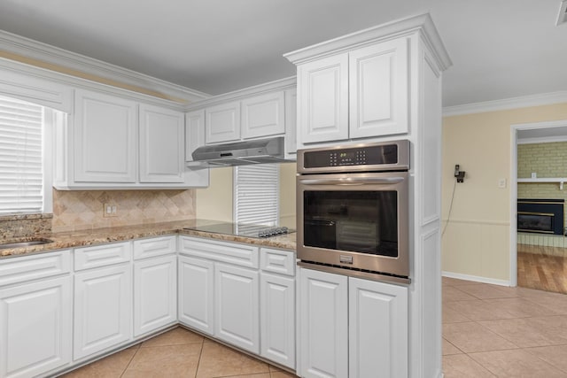 kitchen featuring light tile patterned floors, white cabinetry, ornamental molding, black electric cooktop, and oven