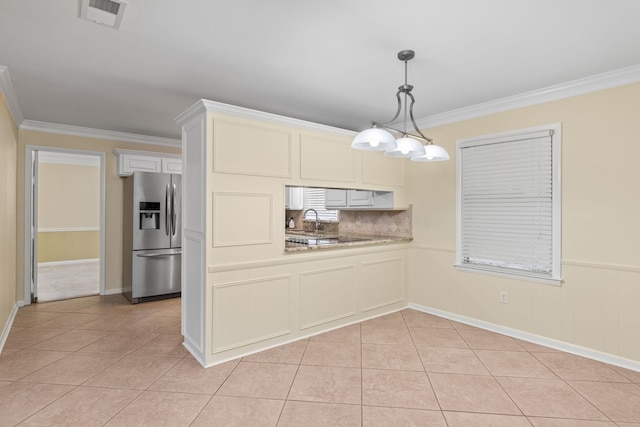 kitchen with stainless steel refrigerator with ice dispenser, light tile patterned flooring, crown molding, decorative light fixtures, and kitchen peninsula