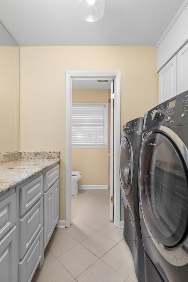 laundry room featuring light tile patterned floors, cabinets, and washing machine and clothes dryer