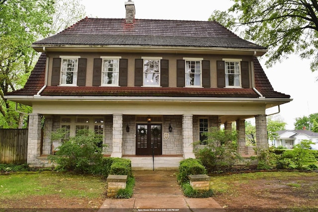  - view of front of home featuring a tile roof, covered porch, a chimney, and french doors