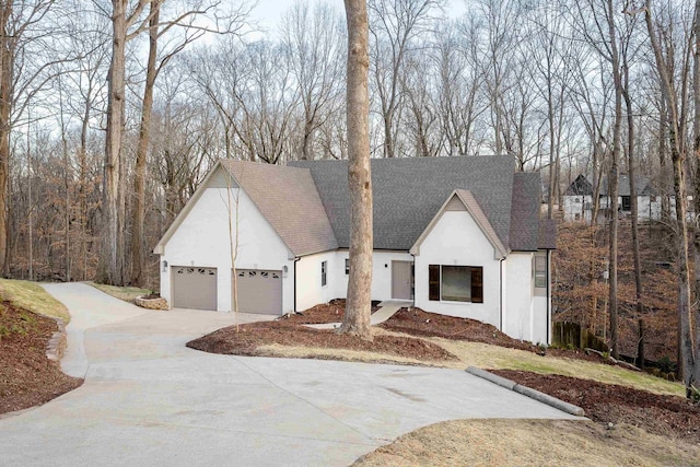 view of front of property with a garage, concrete driveway, roof with shingles, and stucco siding