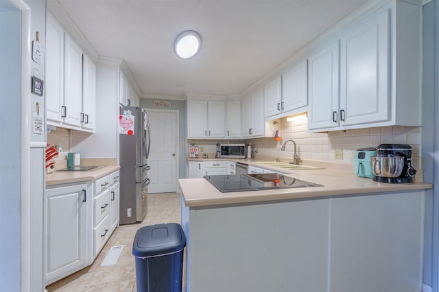  - kitchen featuring appliances with stainless steel finishes, a peninsula, light countertops, white cabinets, and ornamental molding