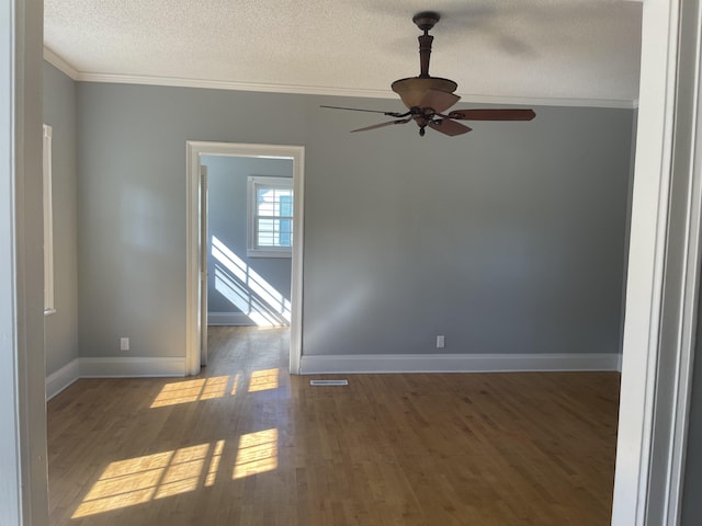 spare room featuring ornamental molding, a textured ceiling, ceiling fan, and dark wood-type flooring