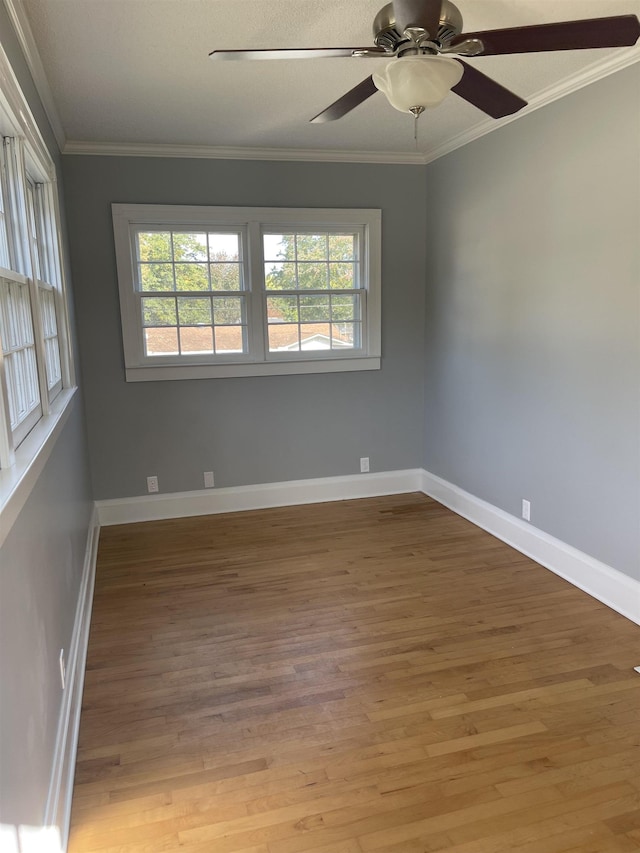 empty room featuring ceiling fan, plenty of natural light, hardwood / wood-style floors, and ornamental molding