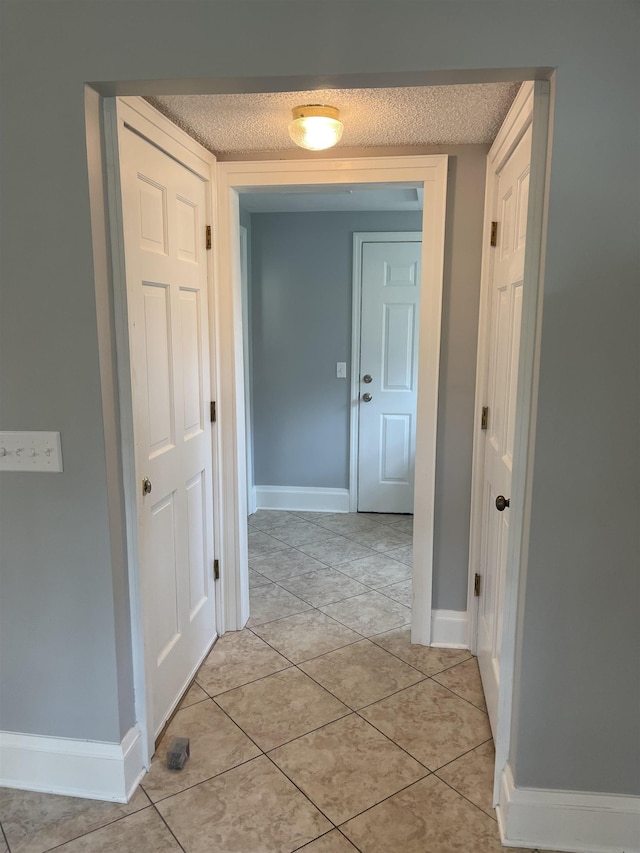 hallway with light tile patterned floors and a textured ceiling