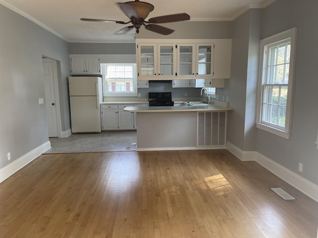 kitchen with kitchen peninsula, white cabinetry, black / electric stove, and white refrigerator