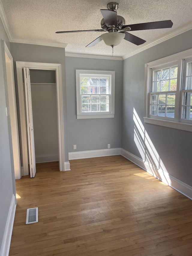 unfurnished bedroom with ceiling fan, light hardwood / wood-style floors, a textured ceiling, and ornamental molding