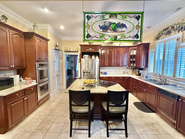 kitchen with a kitchen bar, appliances with stainless steel finishes, light tile patterned floors, and a kitchen island with sink