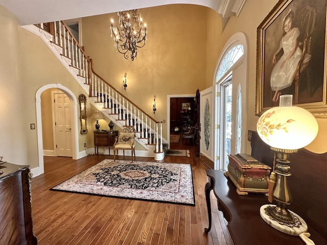 foyer entrance featuring a notable chandelier, dark hardwood / wood-style flooring, and a high ceiling