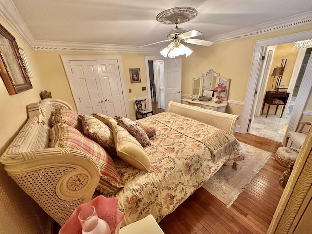 bedroom featuring a closet, light hardwood / wood-style flooring, ceiling fan, and crown molding