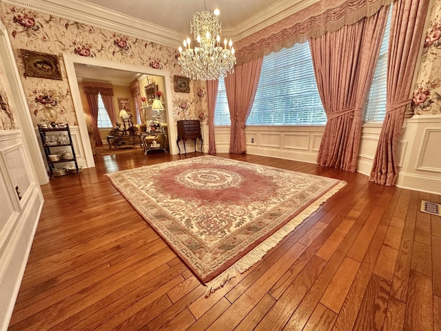 living area with crown molding, a wealth of natural light, dark hardwood / wood-style flooring, and a chandelier