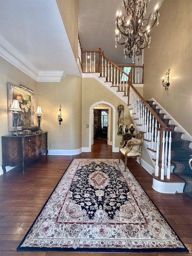 entryway with ornamental molding, a notable chandelier, and hardwood / wood-style flooring