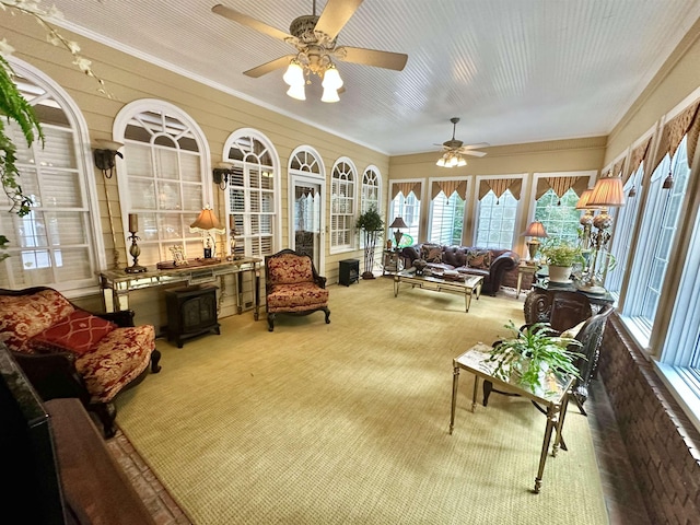 sunroom / solarium featuring ceiling fan and a wood stove