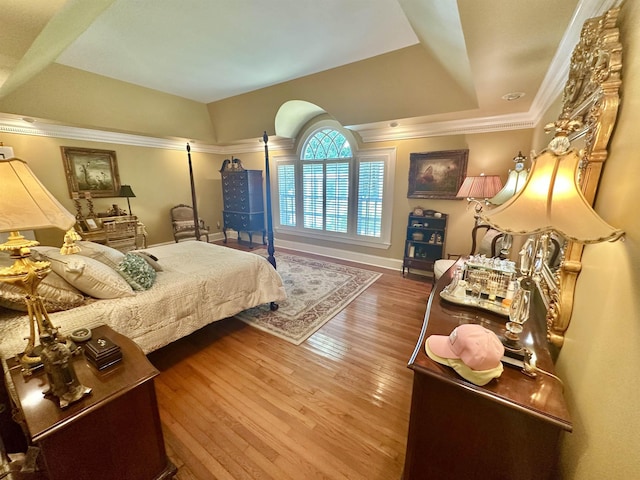 bedroom with hardwood / wood-style flooring, a raised ceiling, and ornamental molding