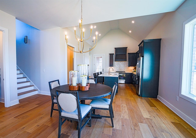 dining space featuring sink, lofted ceiling, light hardwood / wood-style flooring, and a chandelier