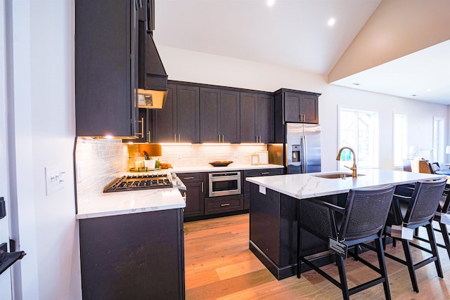 kitchen with decorative backsplash, stainless steel appliances, sink, lofted ceiling, and an island with sink