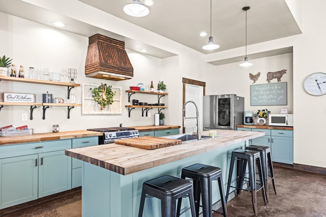 kitchen with blue cabinets, open shelves, stainless steel appliances, a breakfast bar area, and wooden counters