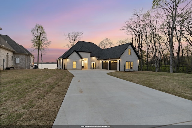  - french country home with a garage, driveway, a lawn, a shingled roof, and brick siding