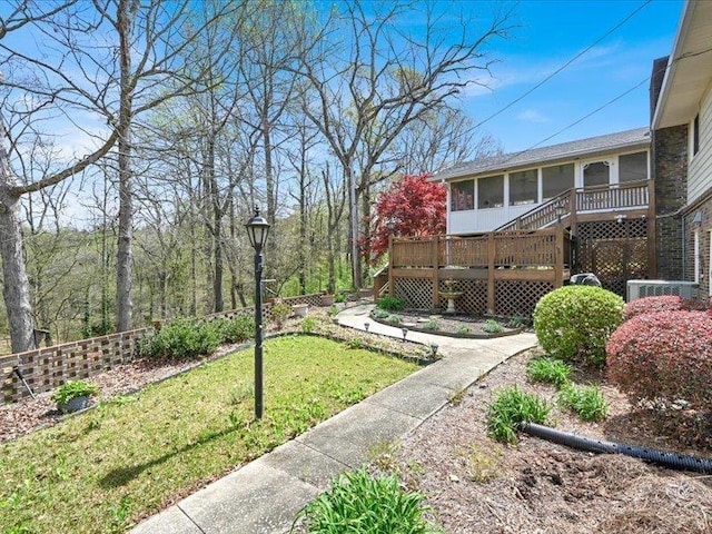 view of yard featuring a sunroom, a wooden deck, and stairs