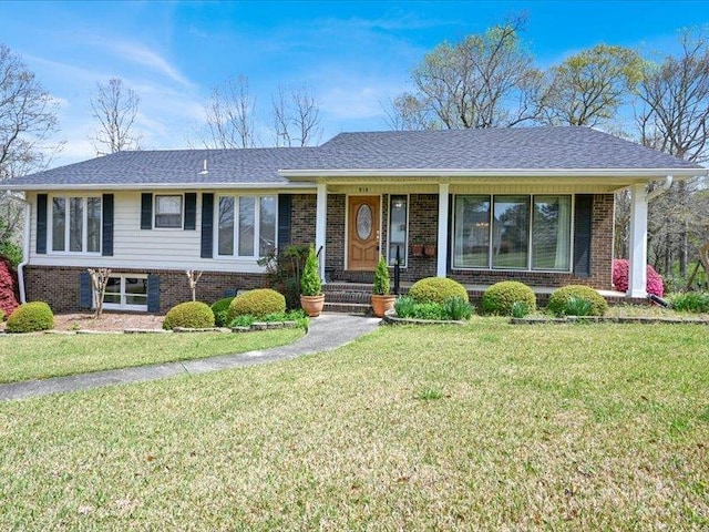 ranch-style home featuring brick siding, a front lawn, and roof with shingles