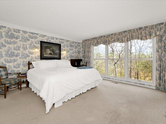 carpeted bedroom featuring multiple windows, wallpapered walls, and visible vents